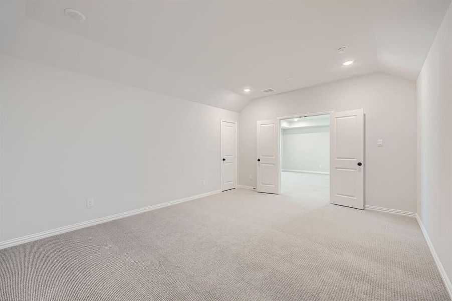 Carpeted spare room with lofted ceiling