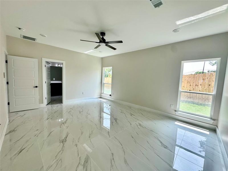 Empty room featuring a ceiling fan, baseboards, light marble finish floors, and a smoke detector