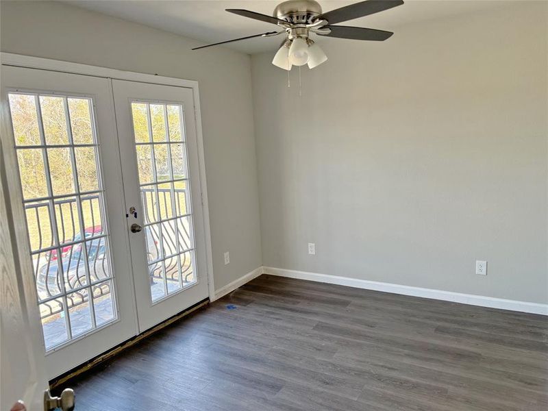 Empty room featuring french doors, dark wood-style floors, and ceiling fan