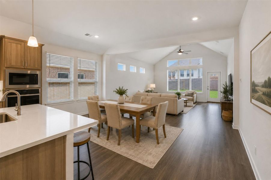 An open concept living and dining area boasts vaulted ceilings and elegant hardwood flooring. Virtually Staged An open concept living and dining area boasts vaulted ceilings and elegant hardwood flooring. Virtually Staged
