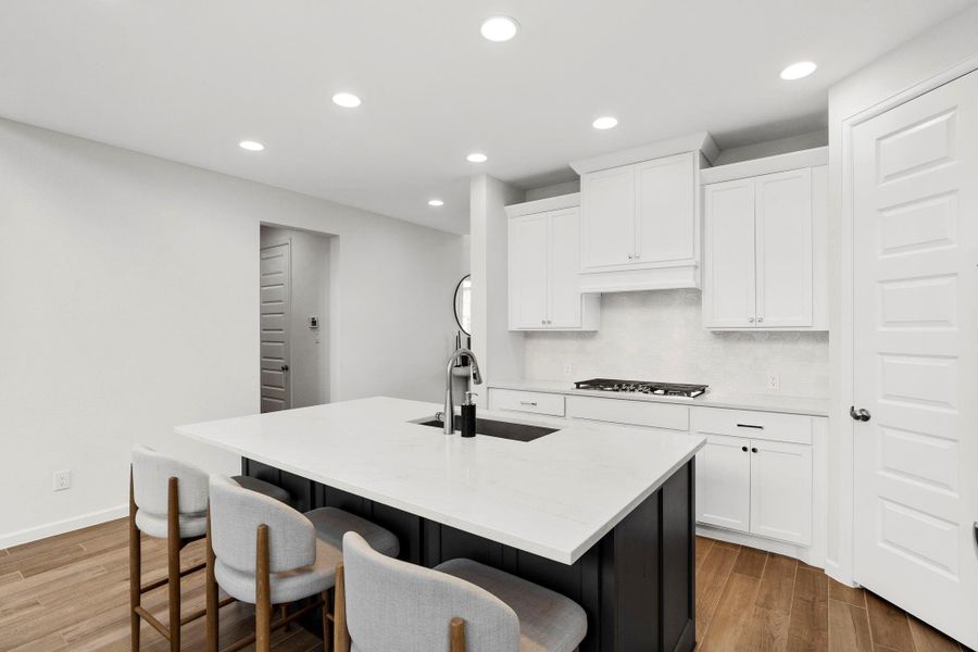 Gourmet kitchen featuring a large island with a breakfast bar, quartz countertops, and a sleek white tile backsplash. Gourmet kitchen featuring a large island with a breakfast bar, quartz countertops, and a sleek white tile backsplash.