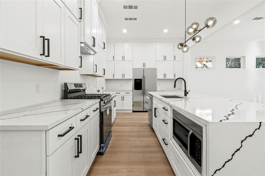 Kitchen with stainless steel appliances, recessed lighting, light stone countertops, light wood-style flooring, and white cabinets