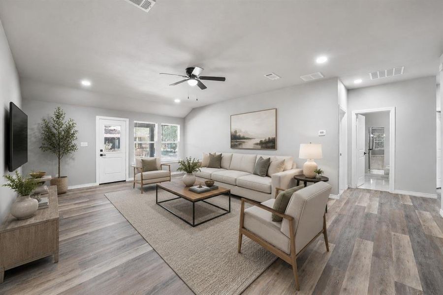 Spacious living area featuring wood-finish flooring, light gray wall tones, and recessed lighting Spacious living area featuring wood-finish flooring, light gray wall tones, and recessed lighting