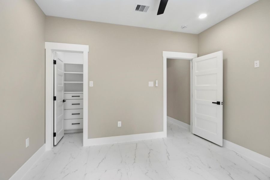 Another angle highlighting the room's smart design, showing a spacious built-in walk-in closet with custom drawers and contemporary black hardware. Another angle highlighting the room's smart design, showing a spacious built-in walk-in closet with custom drawers and contemporary black hardware.