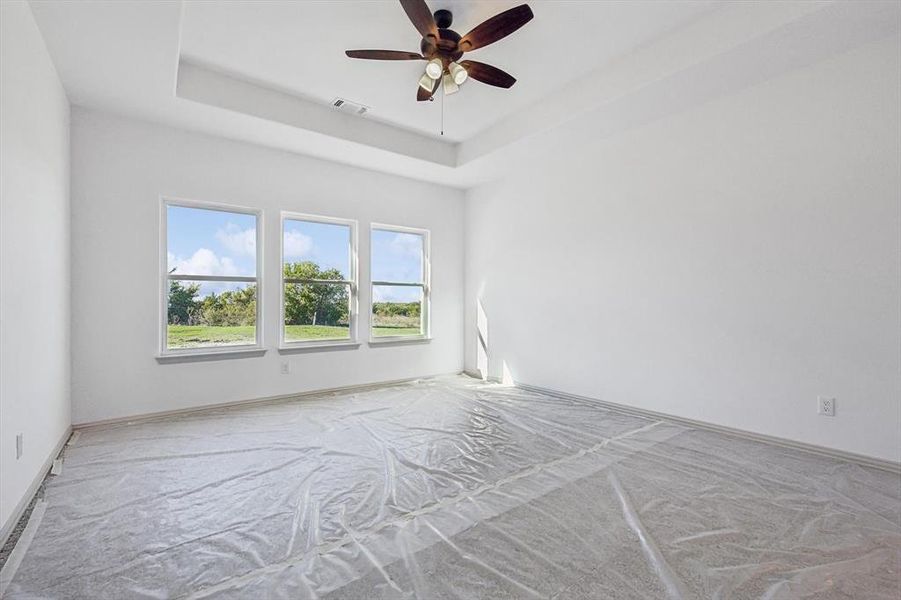 Unfurnished room with ceiling fan, a raised ceiling, and light carpet