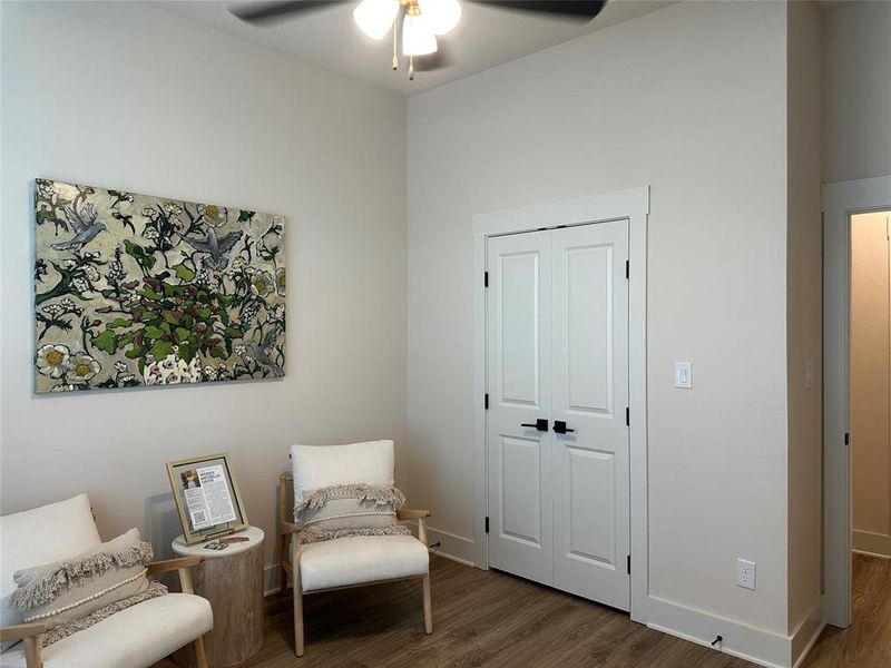 Neutral-toned room featuring a ceiling fan with integrated lighting, wood-finish flooring, white bi-fold doors, and crisp white baseboards