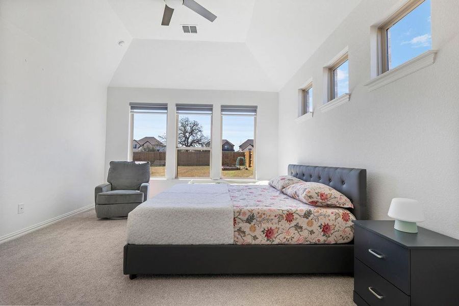 Bedroom with lofted ceiling, a ceiling fan, and light colored carpet Bedroom with lofted ceiling, a ceiling fan, and light colored carpet