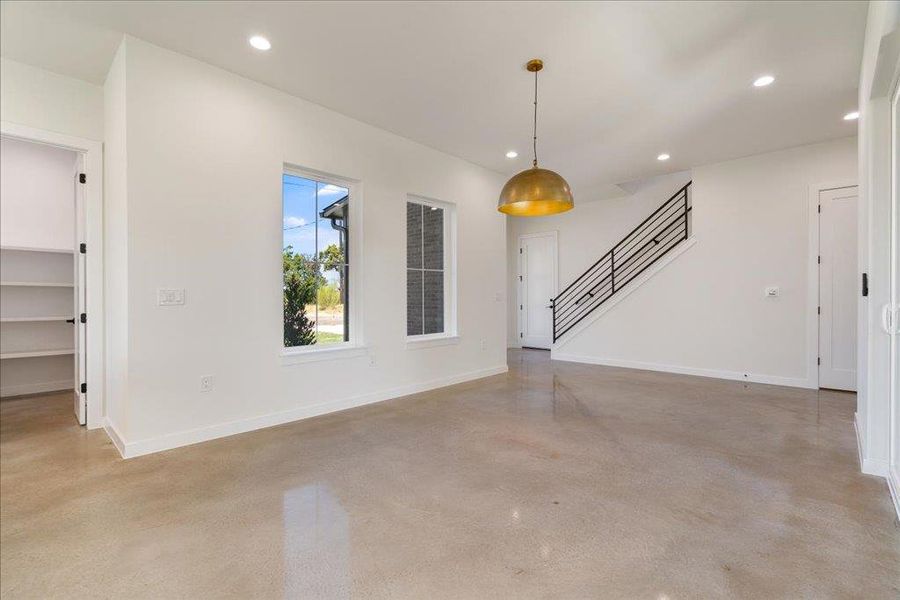 Unfurnished living room featuring recessed lighting, concrete floors, and stairway