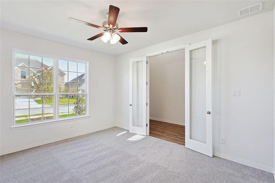 Unfurnished bedroom featuring light carpet, french doors, and ceiling fan