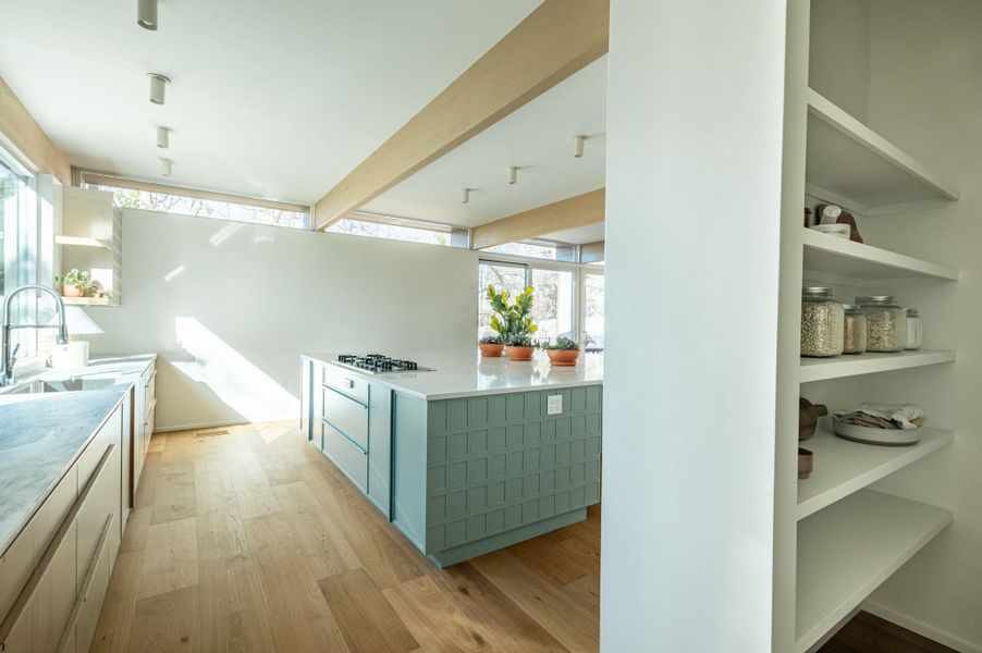 Two tone kitchen with light wood finished floors, open shelves, a kitchen island, two tone color scheme, and beam ceiling