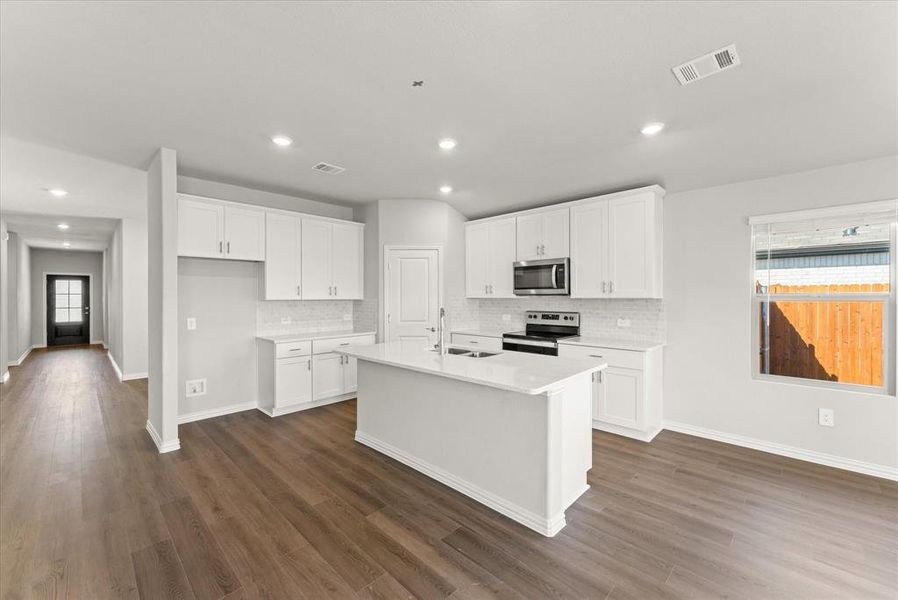 Kitchen featuring a center island with sink, appliances with stainless steel finishes, and white cabinetry