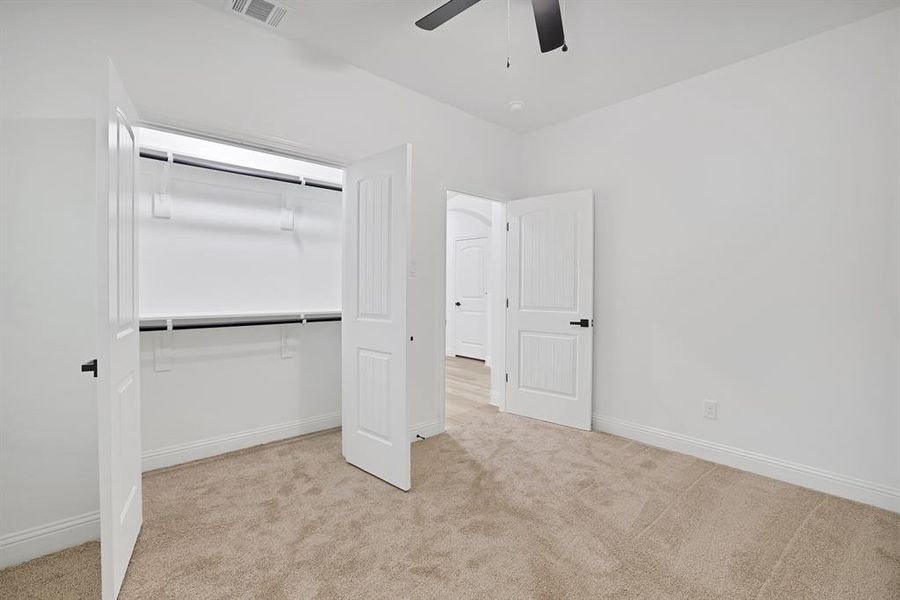 Unfurnished bedroom featuring ceiling fan, light carpet, and a closet