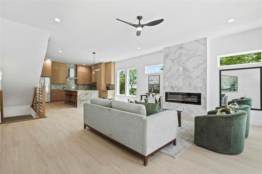 Living room featuring a ceiling fan, a high end fireplace, recessed lighting, and light wood-type flooring Living room featuring a ceiling fan, a high end fireplace, recessed lighting, and light wood-type flooring