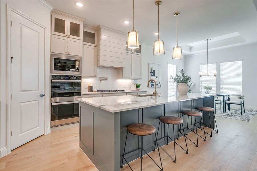 Kitchen with custom cabinets to the ceiling, leathered Quartzite counters, tile backsplash, decorative lighting, ample storage, soft close doors and drawers, and gas cooktop. Kitchen with custom cabinets to the ceiling, leathered Quartzite counters, tile backsplash, decorative lighting, ample storage, soft close doors and drawers, and gas cooktop.