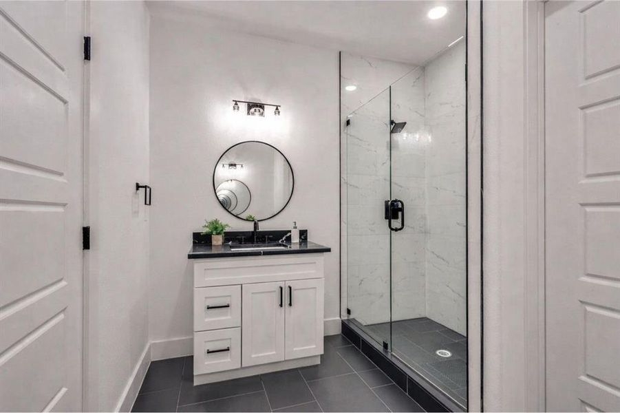 Bathroom featuring a marble finish shower, vanity, tile patterned floors, and recessed lighting