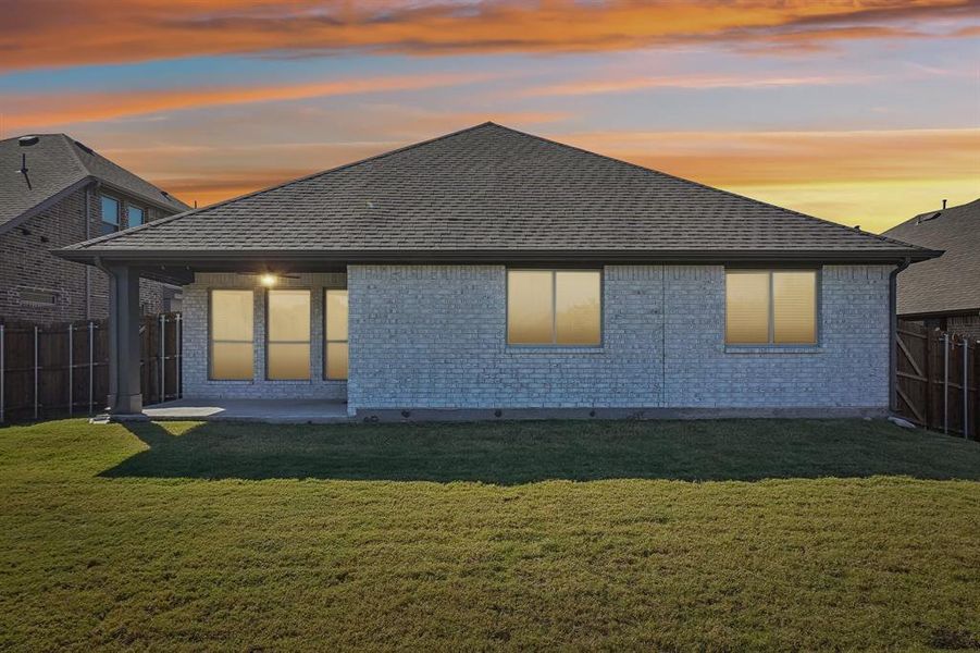 Back house at dusk with spacious yard