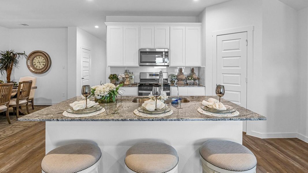 An open concept kitchen with an island with bar seating and access to the living and dining areas.