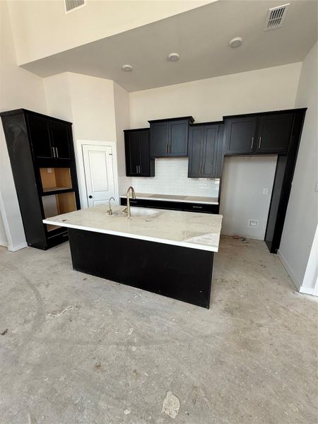 The kitchen style pairs perfectly with the exterior of the home. Dark, moody cabinets with clean, white quartz countertops, finished off with sparkling champagne hardware.