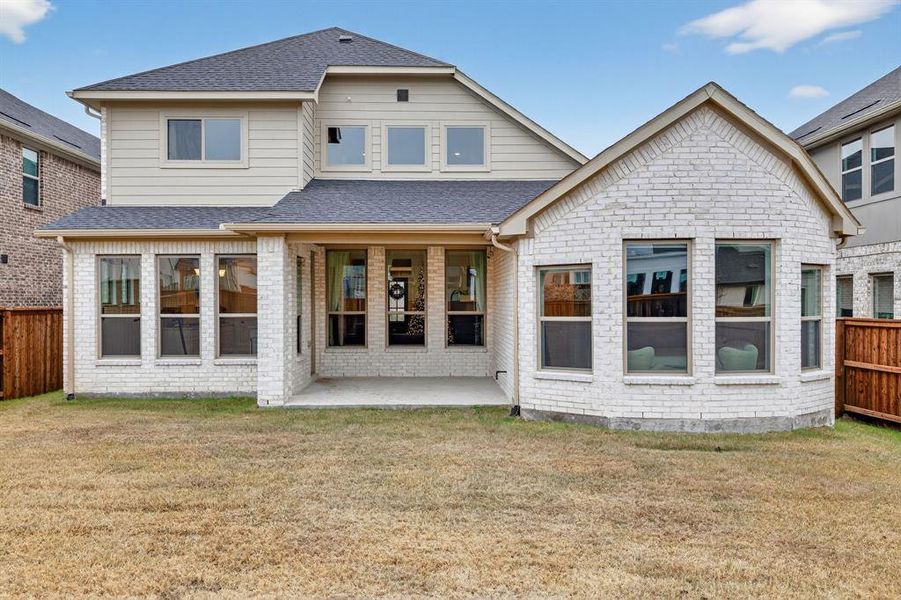 Rear view of property featuring a fenced backyard, brick siding, a patio area, and roof with shingles Rear view of property featuring a fenced backyard, brick siding, a patio area, and roof with shingles