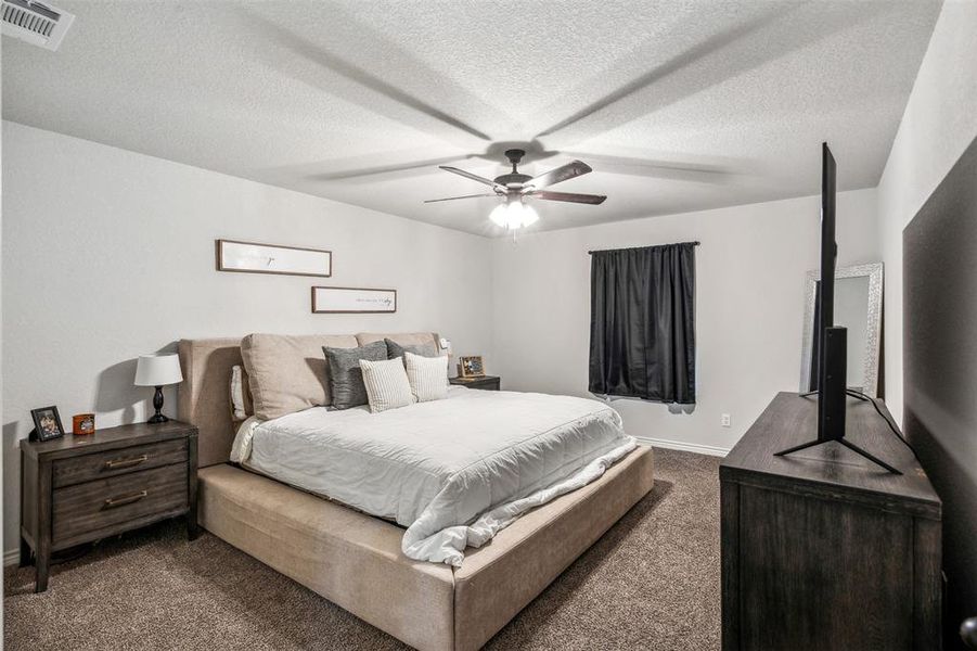 Carpeted bedroom with a textured ceiling and ceiling fan