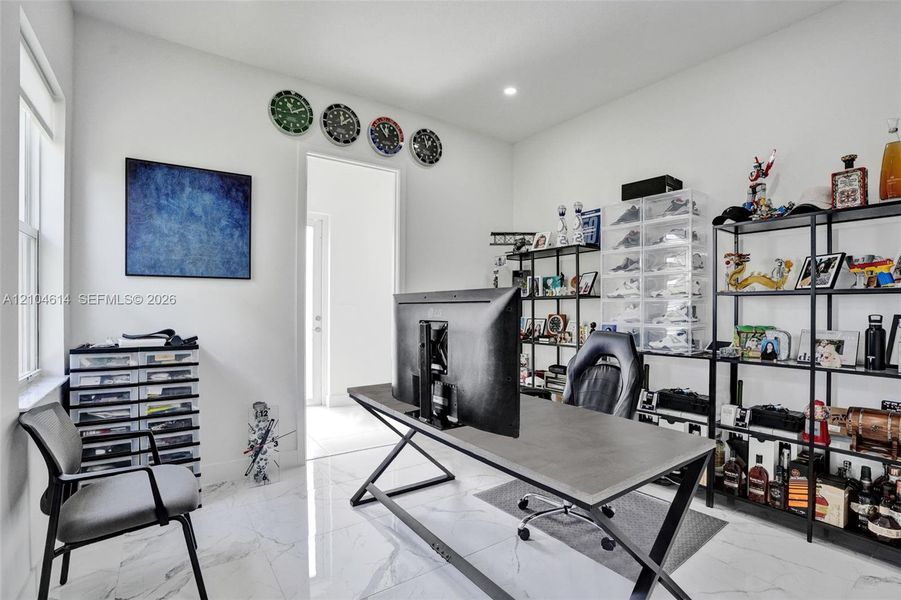 Recessed lighting, marble look flooring, white walls, and a large window