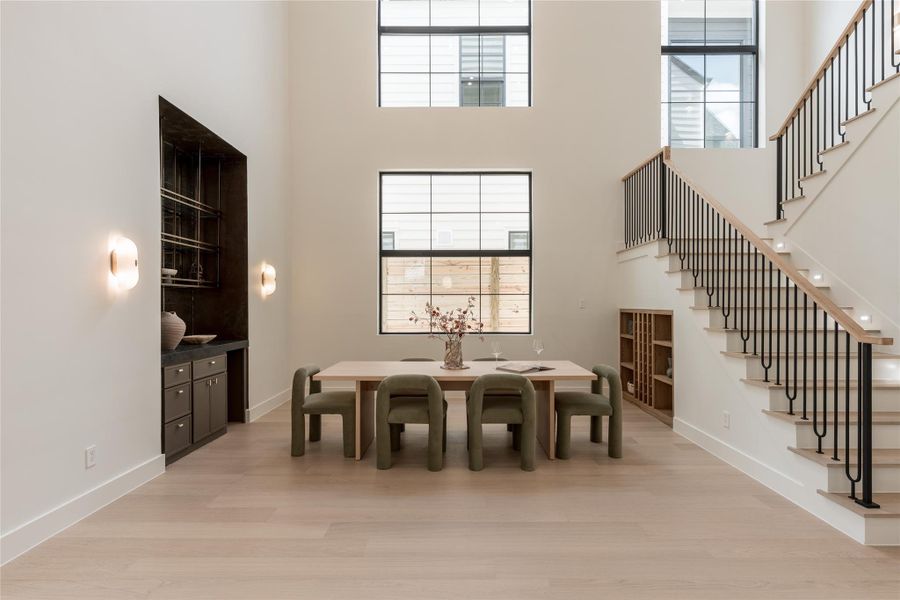 The dramatic two story dining room is framed by soaring windows that draw natural light through the space, while a dedicated dry bar and built in wine cove turn entertaining into part of the architecture. The dramatic two story dining room is framed by soaring windows that draw natural light through the space, while a dedicated dry bar and built in wine cove turn entertaining into part of the architecture.