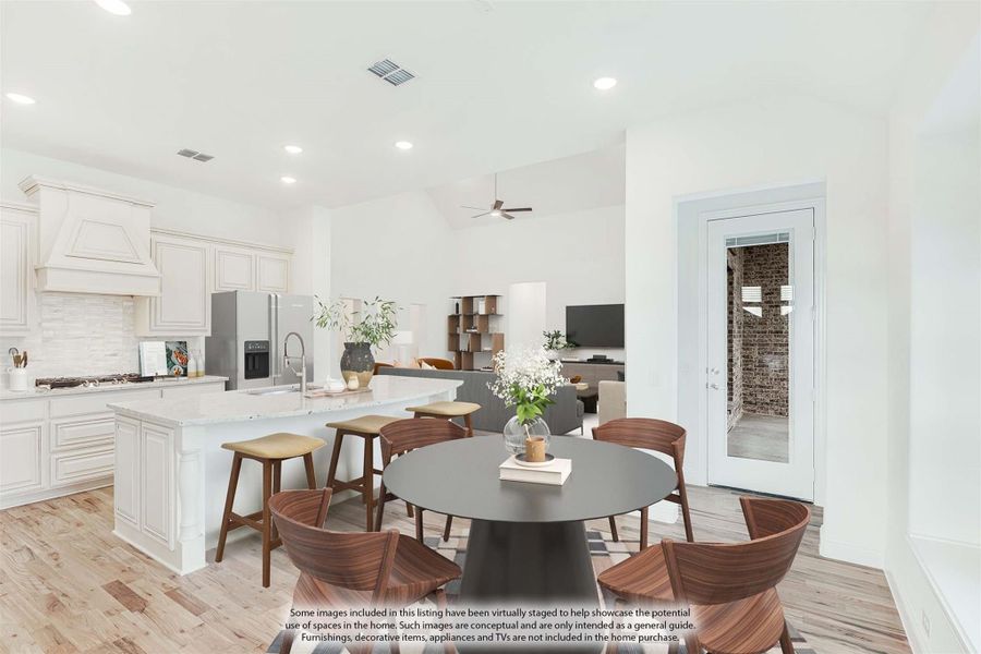 Open-plan kitchen and dining area with white cabinets, large island, round dining table, and wood floors