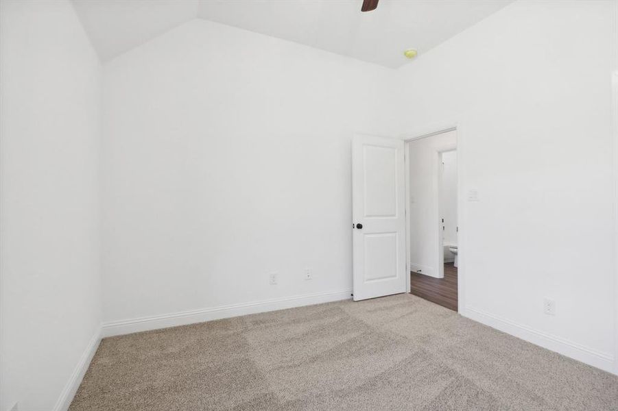 Carpeted empty room featuring lofted ceiling and ceiling fan