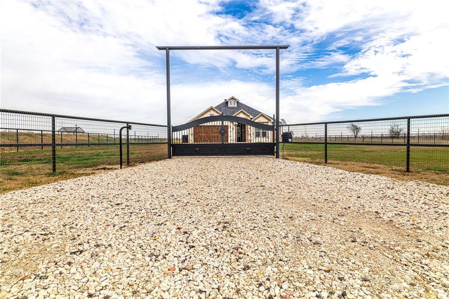 View of home's community featuring a rural view, fence, and a gate