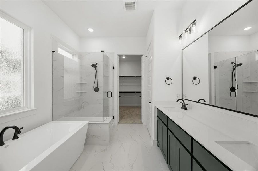 Bathroom with double vanity, a freestanding bath, a marble finish shower, a spacious closet, and light marble finish flooring