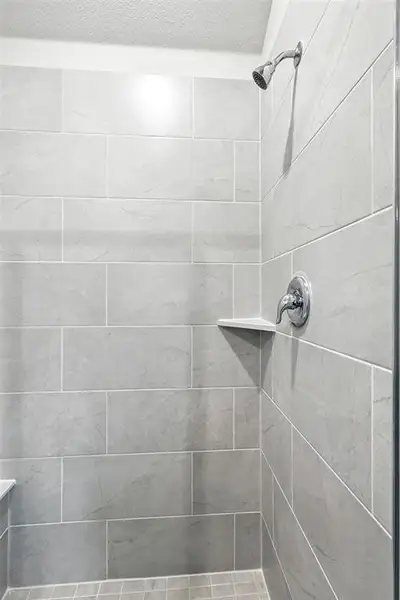 Bathroom with a tile shower and a textured ceiling