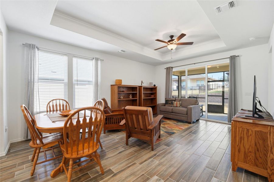 Dining space featuring ceiling fan, wood finish floors, a tray ceiling, and ornamental molding