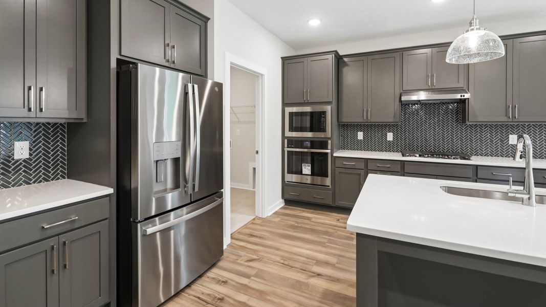 Kitchen with hard surface flooring, quartz countertops, and pendant lighting Kitchen with hard surface flooring, quartz countertops, and pendant lighting