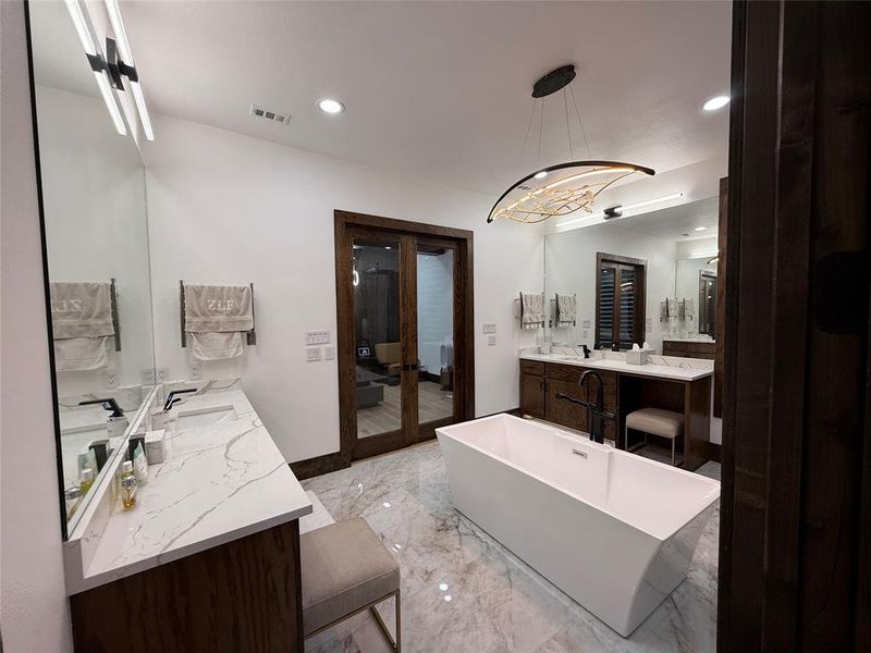 Bathroom featuring a freestanding tub, vanity, recessed lighting, light marble finish floors, and a chandelier