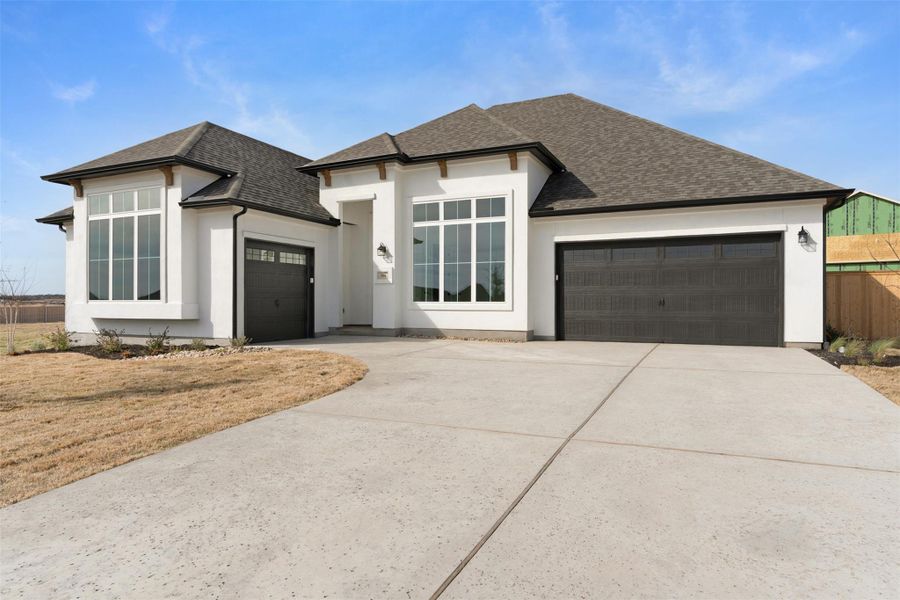 View of front of home with a garage, roof with shingles, concrete driveway, and stucco siding