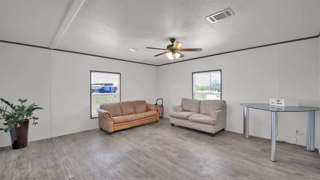 Living room featuring a textured ceiling, plenty of natural light, a ceiling fan, and light wood finished floors