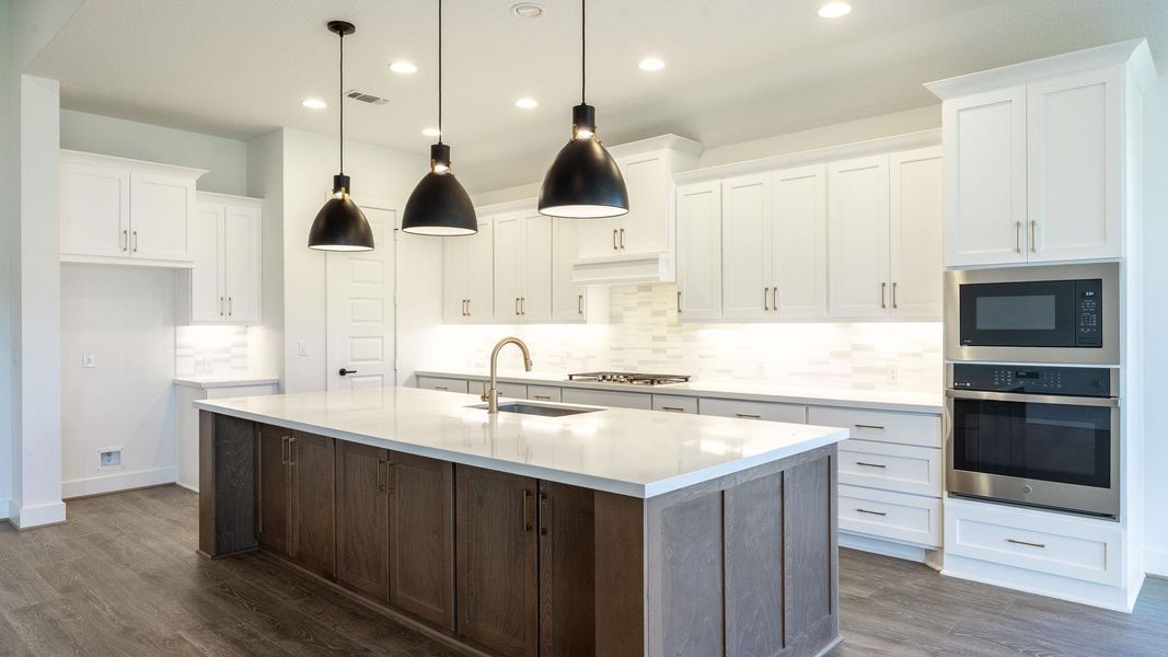 Kitchen featuring backsplash, stainless steel appliances, white cabinets, a center island with sink, and dark wood-style flooring Kitchen featuring backsplash, stainless steel appliances, white cabinets, a center island with sink, and dark wood-style flooring