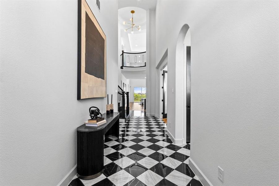 Hallway featuring a towering ceiling and a chandelier Hallway featuring a towering ceiling and a chandelier