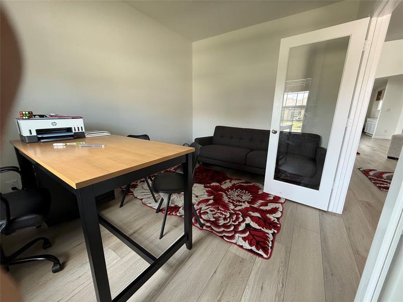 Light-colored wood-finish flooring extends throughout, complemented by white walls and a white multi-pane glass door