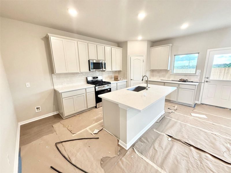 Kitchen with backsplash, appliances with stainless steel finishes, an island with sink, white cabinets, and recessed lighting Kitchen with backsplash, appliances with stainless steel finishes, an island with sink, white cabinets, and recessed lighting