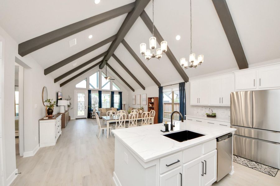 Kitchen opens up to vaulted dining/living with exposed beams.