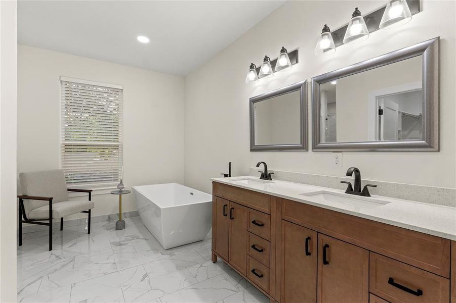 Bathroom featuring double vanity, marble finish floors, a freestanding tub, and recessed lighting Bathroom featuring double vanity, marble finish floors, a freestanding tub, and recessed lighting