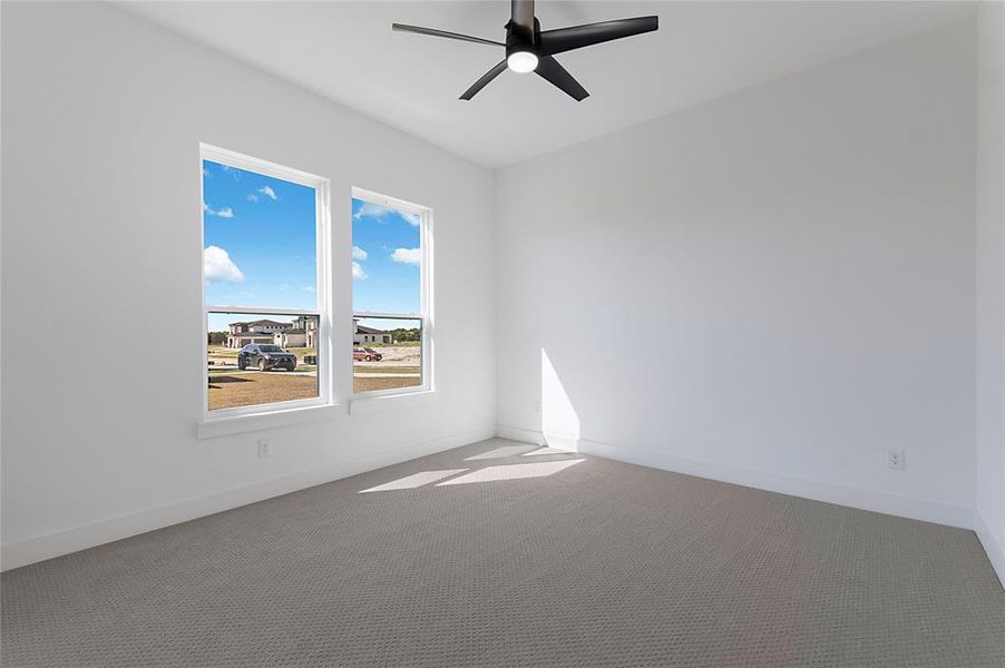 Contemporary interior featuring two large double-hung windows, a modern ceiling fan with integrated lighting, pristine white walls, and plush carpet flooring Contemporary interior featuring two large double-hung windows, a modern ceiling fan with integrated lighting, pristine white walls, and plush carpet flooring
