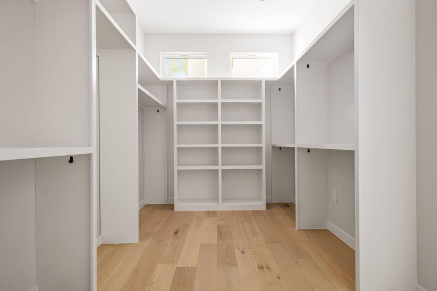 Ample custom shelving and warm hardwood flooring define this organized walk-in closet space. Ample custom shelving and warm hardwood flooring define this organized walk-in closet space.