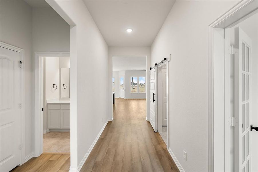 Corridor featuring a barn door, light wood finished floors, and recessed lighting