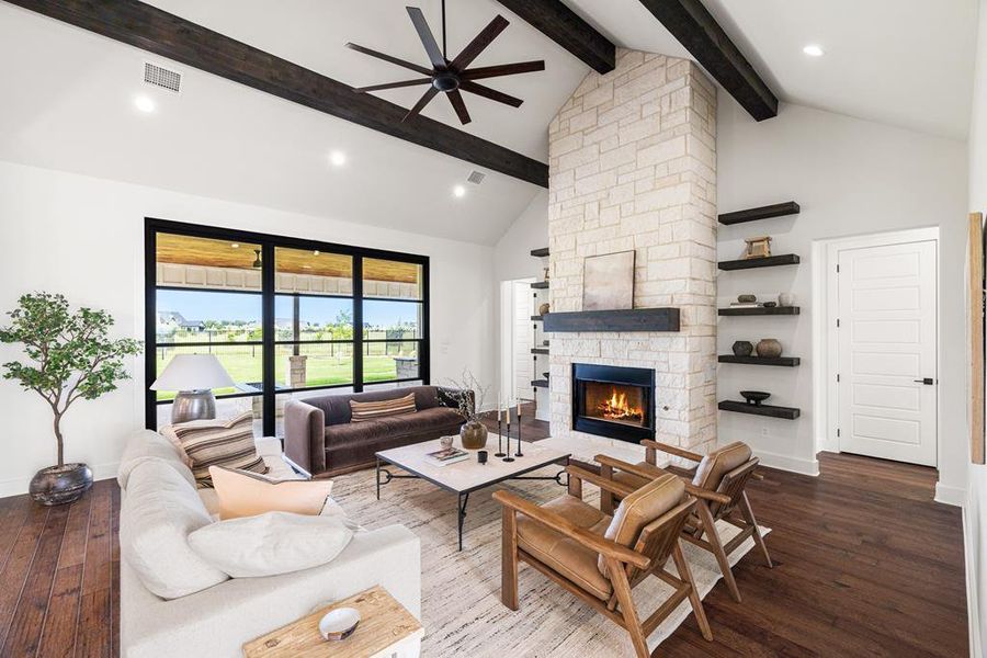 Virtually stage Living area featuring high vaulted ceiling, dark engineered wood-style flooring, stone fireplace, ceiling fan and beamed ceiling Virtually stage Living area featuring high vaulted ceiling, dark engineered wood-style flooring, stone fireplace, ceiling fan and beamed ceiling