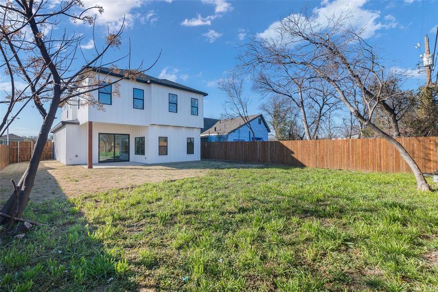 Back of house with a lawn and a patio