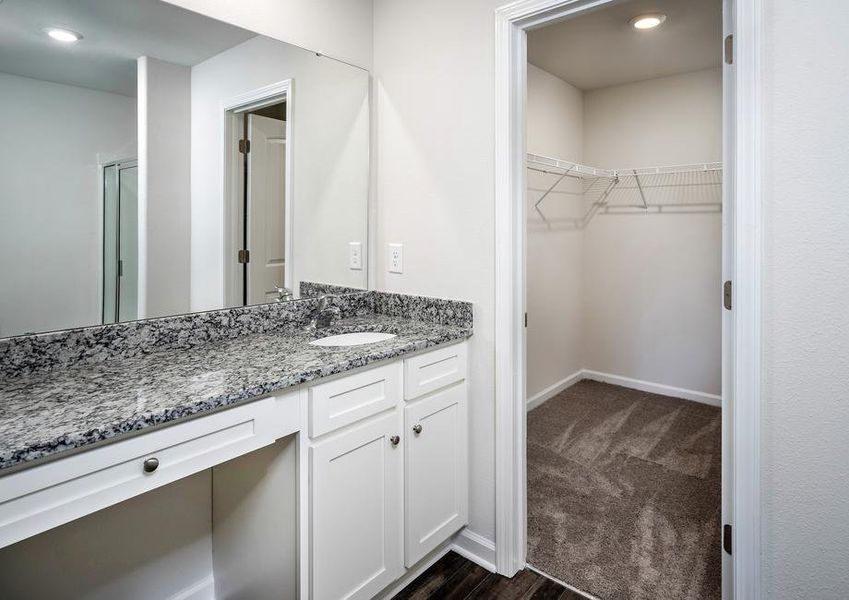 Master bathroom with large vanity, white cabinets, granite countertops and access to a walk-in closet.