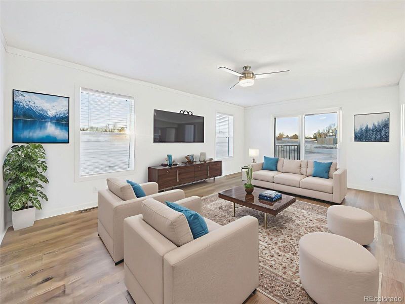 Living Room Virtually Staged A spacious and sunlit living area with large windows, modern ceiling fan, and seamless access to the backyard through sliding glass doors—ideal for gathering or relaxing.