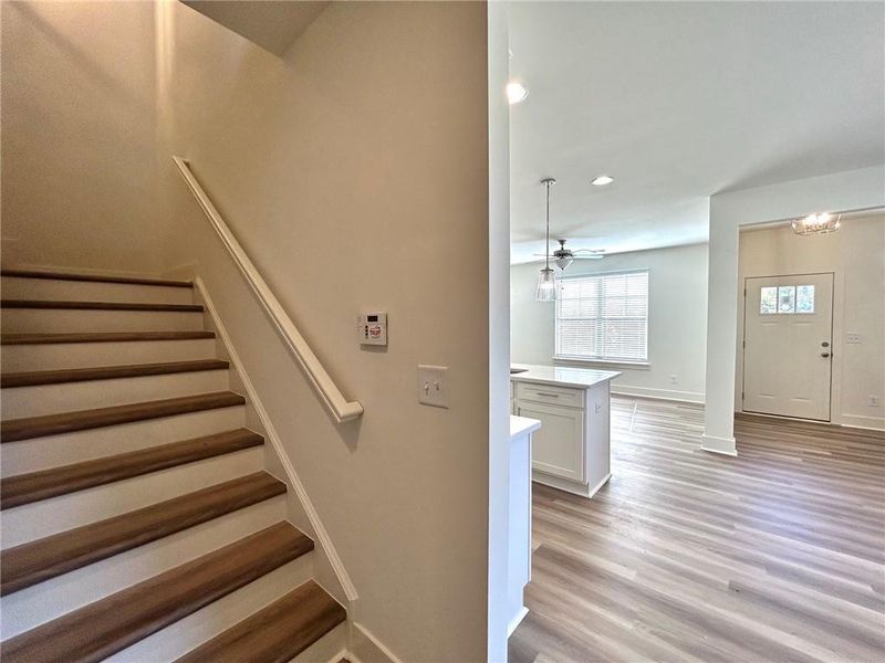 Stairway featuring light hardwood / wood-style flooring and ceiling fan with notable chandelier